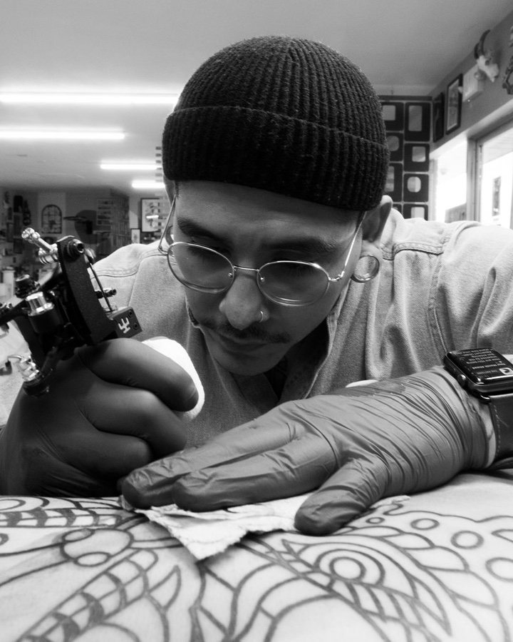 Portrait of D, tattoo artist at Lucky Rose, tattooing a client