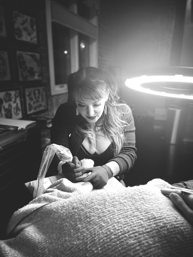 Portrait of Megan, tattoo artist at Lucky Rose, tattooing a client